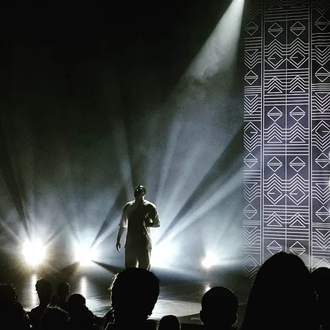 Dino D'Santiago no palco com projeção ao fundo